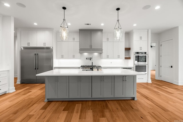 41 Haywood Ct, Little Rock, AR 72223 - kitchen with stainless steel appliances, light wood-type flooring, light countertops, a spacious island, and white cabinetry