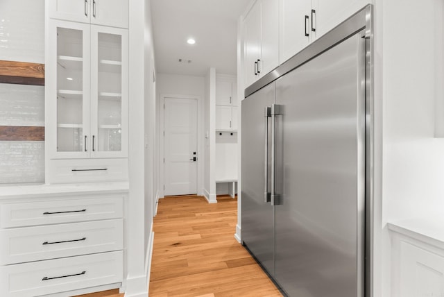 41 Haywood Ct, Little Rock, AR 72223 - kitchen with stainless steel built in fridge, white cabinetry, glass insert cabinets, light wood finished floors, and recessed lighting