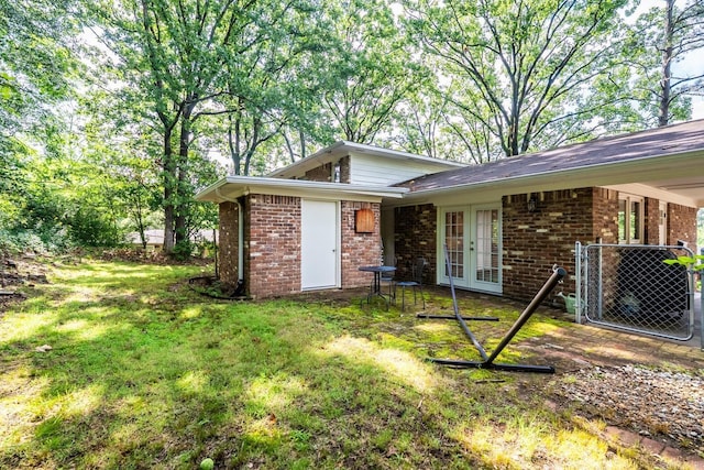 7002 Amherst Dr, Little Rock, AR 72205 - view of home's exterior with french doors, brick siding, and a lawn