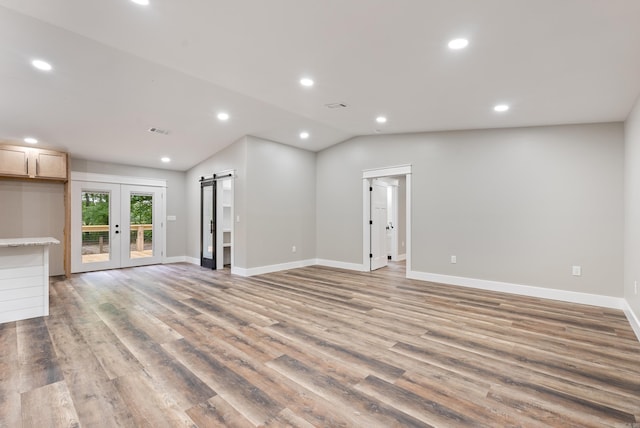 26 W Mobbs Cir, Greenbrier, AR 72058 - unfurnished living room featuring lofted ceiling, recessed lighting, light wood-style flooring, french doors, and a barn door