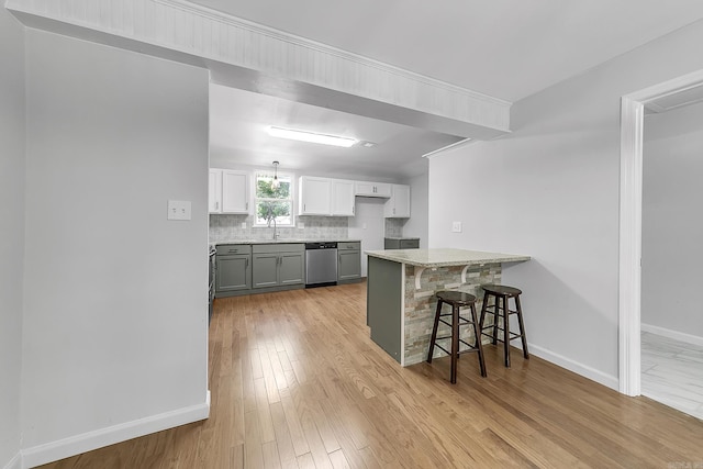 1550 E Main St, Austin, AR 72007 - kitchen with stainless steel dishwasher, a peninsula, a breakfast bar, backsplash, and light wood-style flooring
