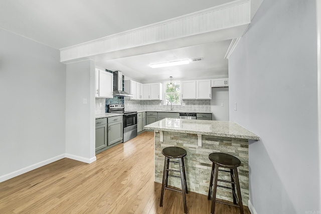 1550 E Main St, Austin, AR 72007 - kitchen with appliances with stainless steel finishes, wall chimney range hood, decorative backsplash, a kitchen bar, and light wood-style flooring