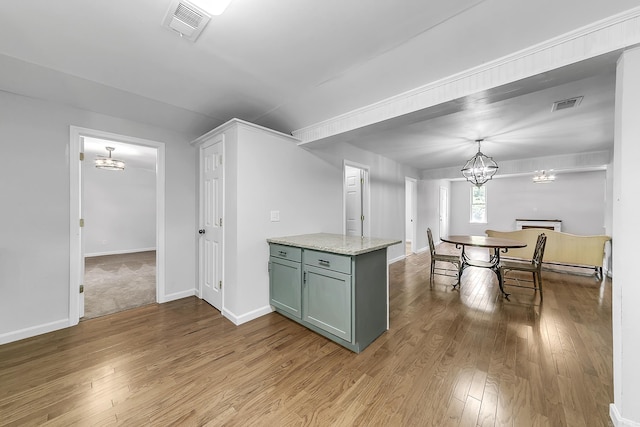 1550 E Main St, Austin, AR 72007 - kitchen featuring a chandelier, hardwood / wood-style floors, light stone countertops, and pendant lighting