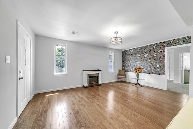 1550 E Main St, Austin, AR 72007 - unfurnished living room featuring healthy amount of natural light, wood finished floors, a chandelier, a glass covered fireplace, and wallpapered walls