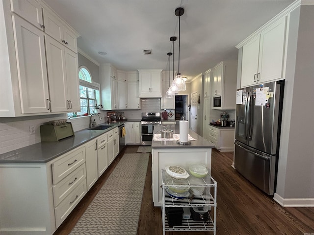 1715 Royal Dr, Conway, AR 72034 - kitchen with appliances with stainless steel finishes, dark wood-style flooring, white cabinets, and a center island