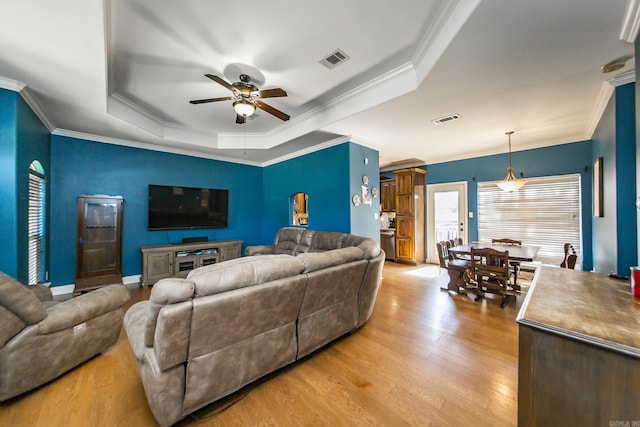 3200 Overcup Dr, Sherwood, AR 72120 - living room featuring a raised ceiling, ceiling fan, ornamental molding, and light wood-type flooring