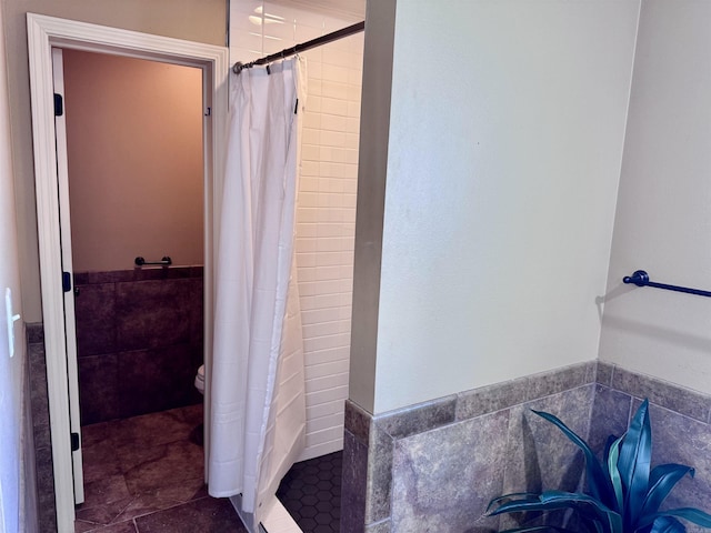 full bathroom with a stall shower, tile walls, and wainscoting