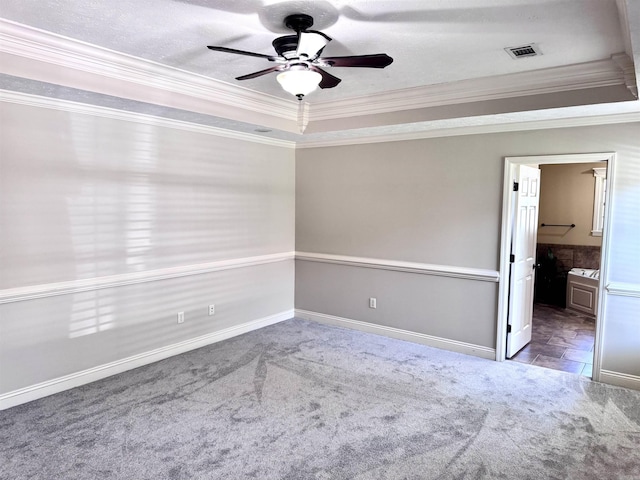 carpeted empty room featuring crown molding, a tray ceiling, and a ceiling fan