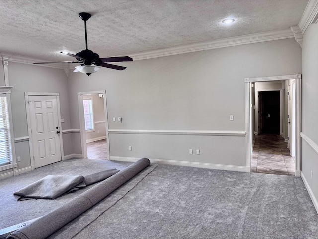 carpeted living area with a textured ceiling, ornamental molding, and a ceiling fan