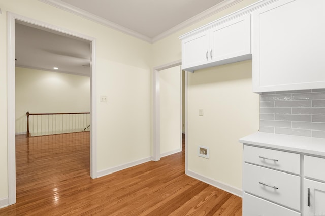 2219 Westport Loop, Little Rock, AR 72212 - kitchen with light wood-style floors, tasteful backsplash, ornamental molding, light countertops, and white cabinetry