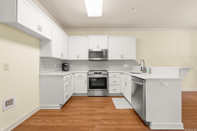 2219 Westport Loop, Little Rock, AR 72212 - kitchen with appliances with stainless steel finishes, a peninsula, decorative backsplash, and white cabinetry