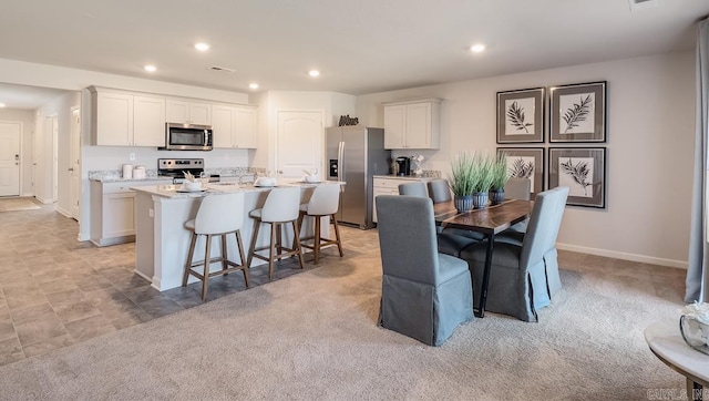 dining space featuring recessed lighting and light carpet