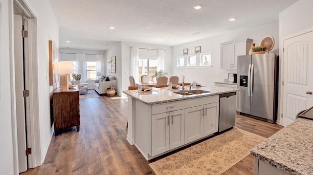 3416 Hank Dr, Jonesboro, AR 72404 - kitchen featuring appliances with stainless steel finishes, light wood-type flooring, a center island with sink, recessed lighting, and light stone countertops