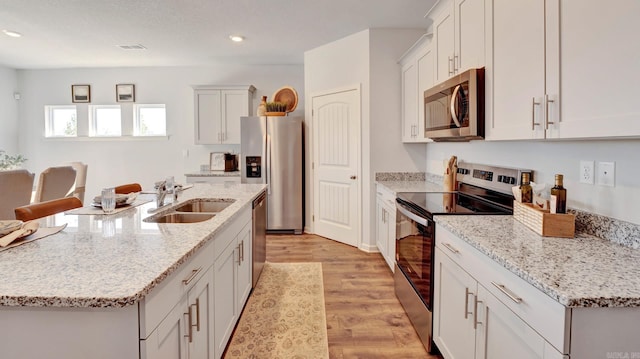 3416 Hank Dr, Jonesboro, AR 72404 - kitchen featuring stainless steel appliances, light wood-type flooring, recessed lighting, a center island with sink, and white cabinets