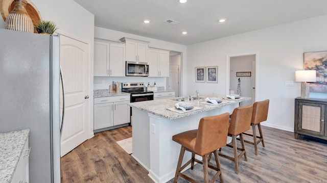 3416 Hank Dr, Jonesboro, AR 72404 - kitchen with appliances with stainless steel finishes, wood finished floors, a kitchen breakfast bar, recessed lighting, and white cabinets