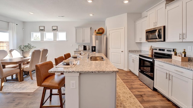 3416 Hank Dr, Jonesboro, AR 72404 - kitchen with appliances with stainless steel finishes, a kitchen bar, a center island with sink, recessed lighting, and light wood-style flooring