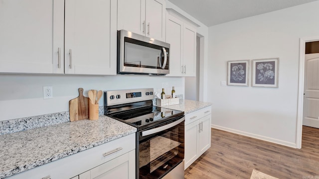 3416 Hank Dr, Jonesboro, AR 72404 - kitchen featuring appliances with stainless steel finishes, light wood-style flooring, light stone counters, and white cabinetry