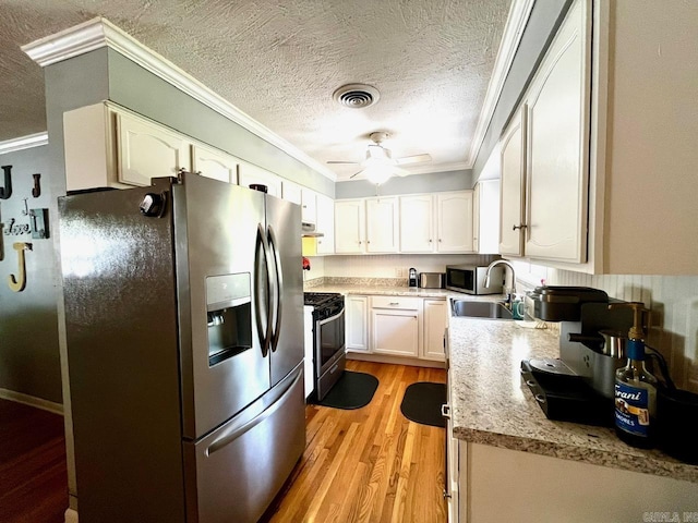 6312 Sandy Ln, Little Rock, AR 72204 - kitchen featuring appliances with stainless steel finishes, crown molding, light wood-type flooring, white cabinets, and ceiling fan