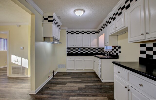9425 S 365th Hwy, Little Rock, AR 72206 - kitchen with dark countertops, crown molding, dark wood-style floors, backsplash, and white cabinetry