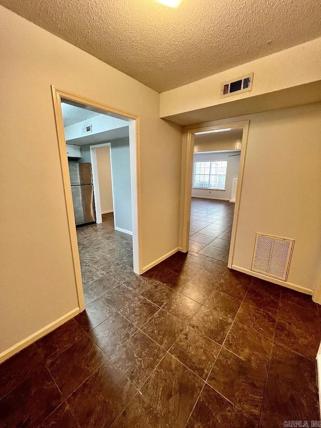 spare room with baseboards and a textured ceiling