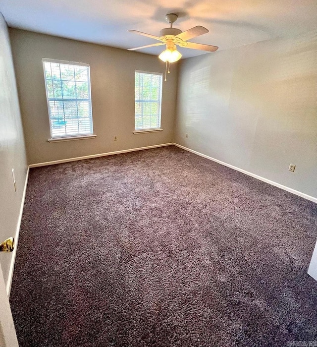 carpeted spare room with ceiling fan and baseboards