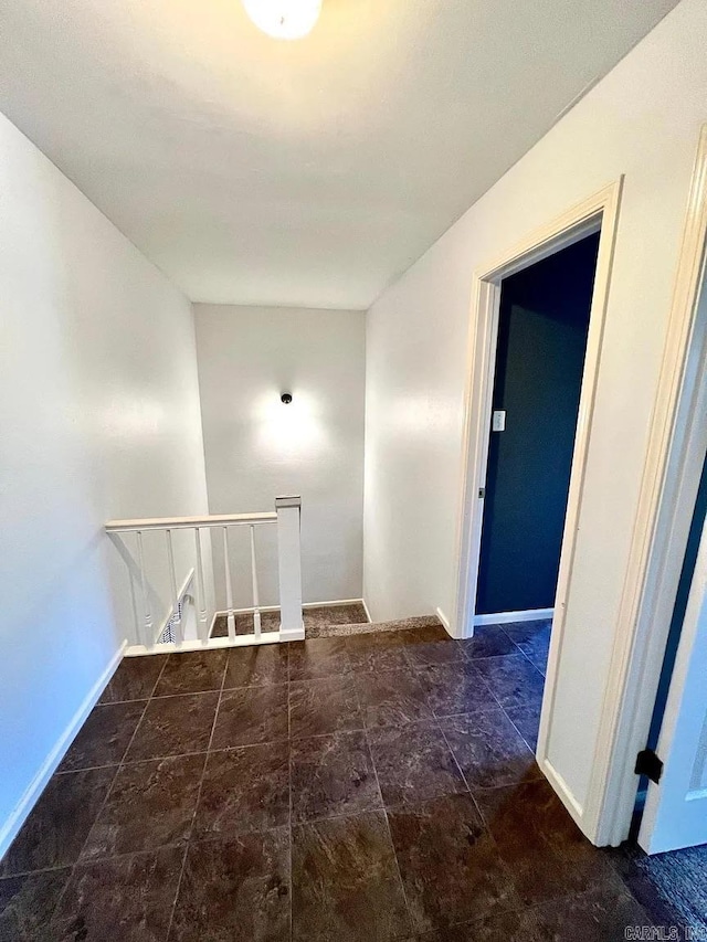 corridor featuring an upstairs landing and baseboards
