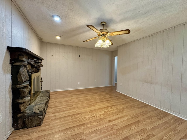 701 Emerald Gardens Dr, North Little Rock, AR 72118 - unfurnished living room with light wood finished floors, wood walls, a textured ceiling, ceiling fan, and a fireplace