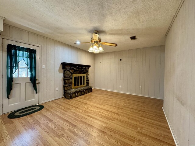 701 Emerald Gardens Dr, North Little Rock, AR 72118 - unfurnished living room featuring light wood-style floors, a textured ceiling, ceiling fan, a fireplace, and wood walls