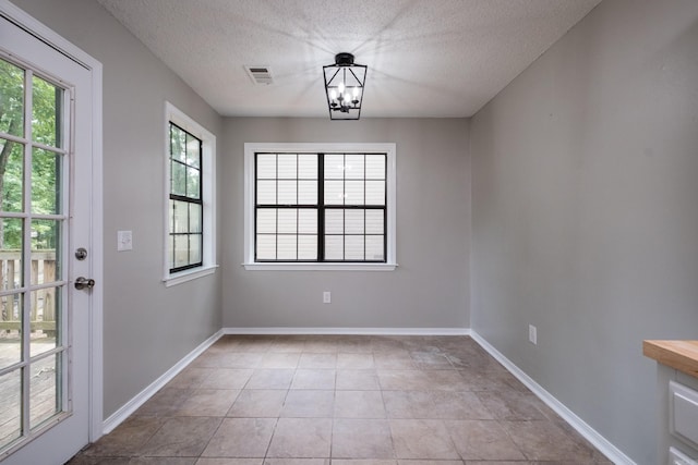 311 Nix Rd, Little Rock, AR 72211 - unfurnished dining area featuring a textured ceiling, a chandelier, and light tile patterned flooring
