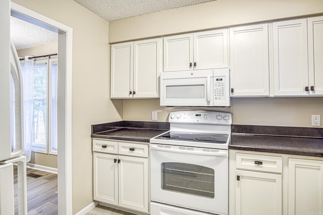 1 Halcon Pl, Hot Springs Village, AR 71909 - kitchen with white appliances, a textured ceiling, dark countertops, healthy amount of natural light, and white cabinetry
