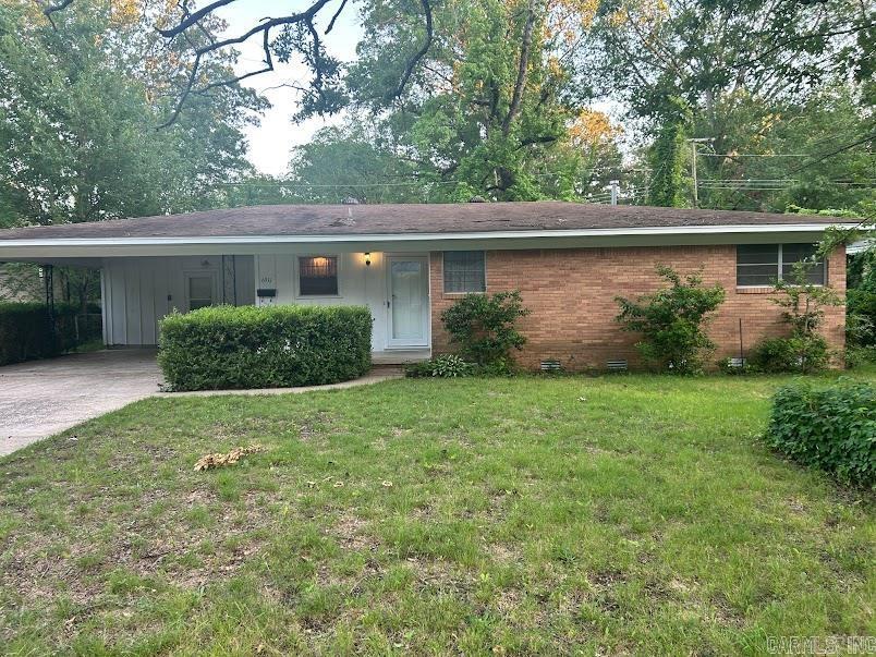 single story home featuring a front lawn, driveway, brick siding, an attached carport, and crawl space