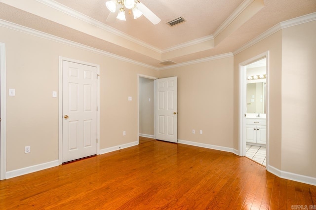 1940 Payne Ln, Conway, AR 72034 - unfurnished bedroom with light wood-style flooring, a tray ceiling, crown molding, ensuite bath, and ceiling fan