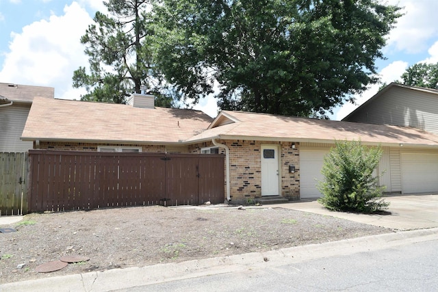 34 Hampshire Cir, Little Rock, AR 72212 - view of front of home with brick siding, an attached garage, a chimney, a gate, and driveway