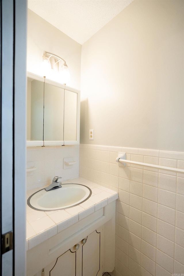 3109 Donaghey Dr, North Little Rock, AR 72116 - bathroom with vanity, a wainscoted wall, and tile walls