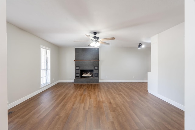 3109 Donaghey Dr, North Little Rock, AR 72116 - unfurnished living room featuring wood finished floors, ceiling fan, and a brick fireplace