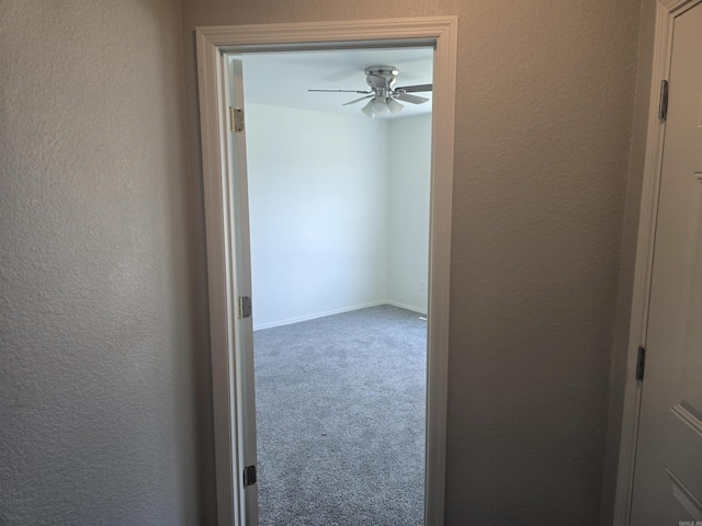 hallway with carpet floors and a textured wall