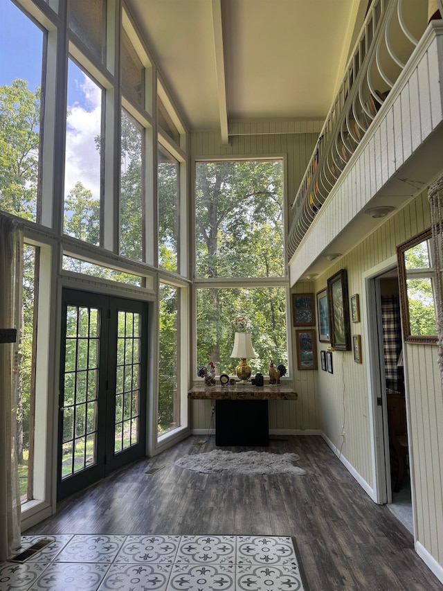 unfurnished sunroom featuring french doors, healthy amount of natural light, and beamed ceiling