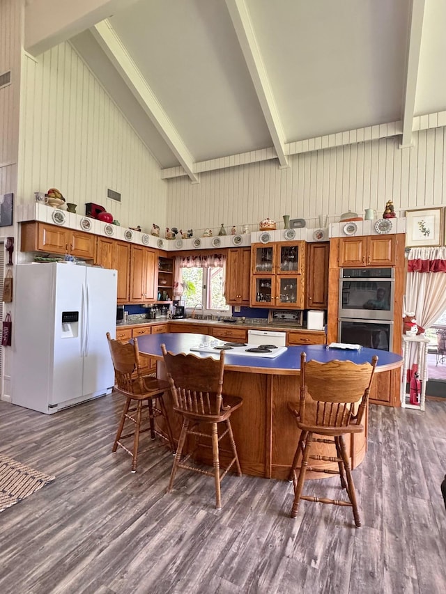 kitchen with white appliances, brown cabinetry, dark wood-style flooring, a large island, and glass insert cabinets