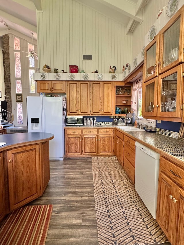 kitchen with white appliances, dark wood-style flooring, brown cabinetry, beamed ceiling, and high vaulted ceiling
