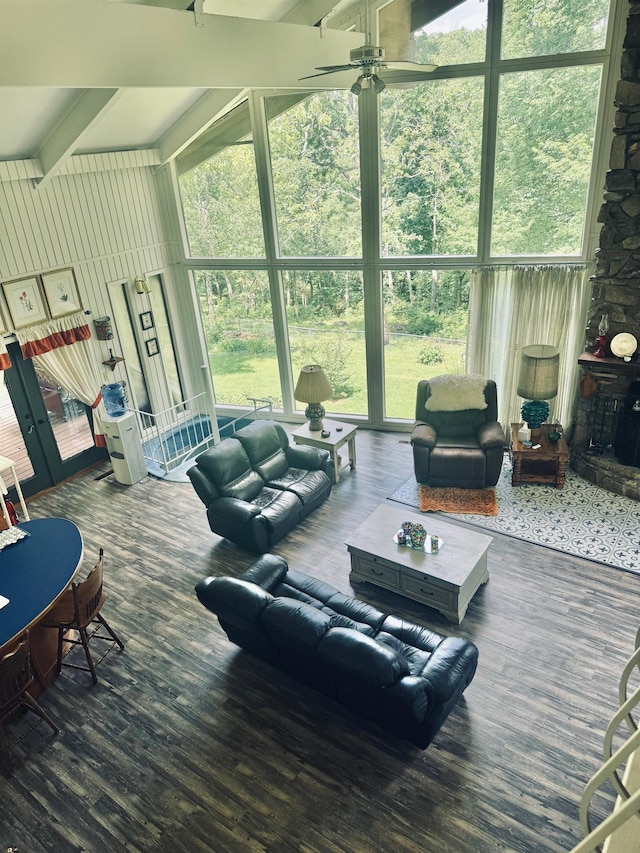 living room featuring a ceiling fan, a high ceiling, wood finished floors, and beamed ceiling