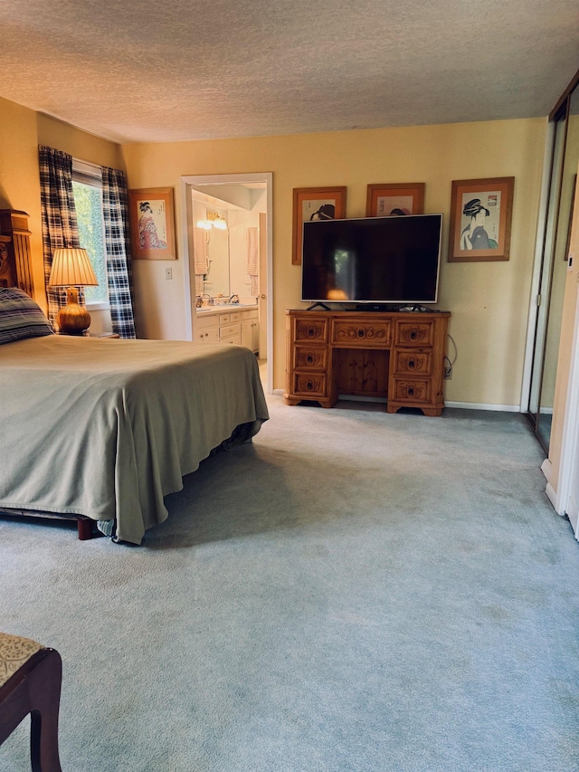 carpeted bedroom with a textured ceiling and connected bathroom