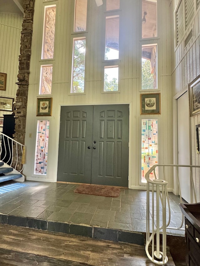 entryway with a towering ceiling, wood walls, and stairs