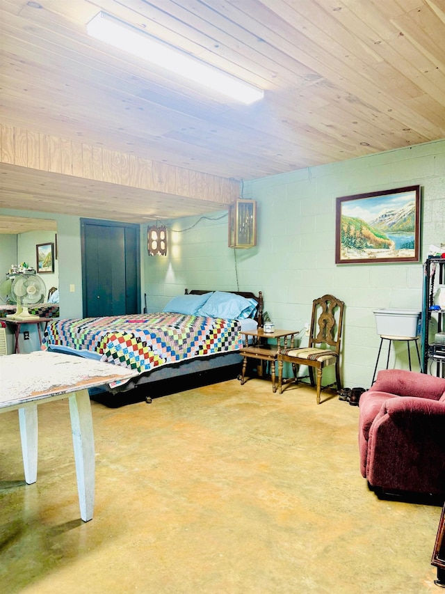 bedroom with finished concrete flooring and concrete block wall
