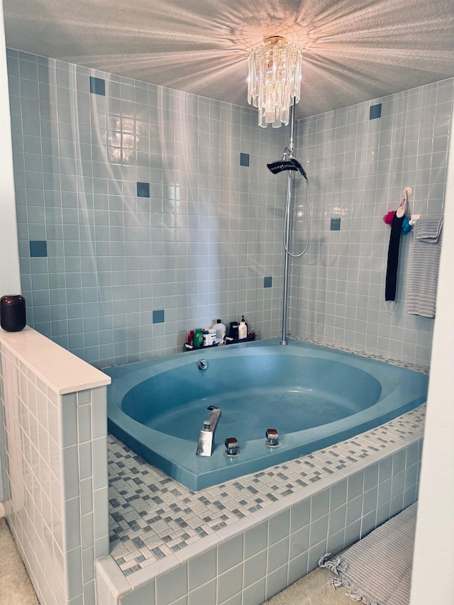 full bathroom with tiled bath, tile walls, and a chandelier