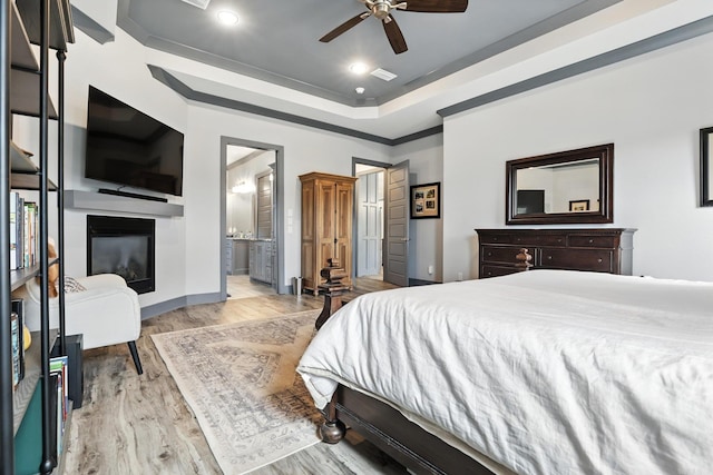 6756 Hilo St, Benton, AR 72019 - bedroom with light wood-style flooring, a glass covered fireplace, a tray ceiling, ensuite bath, and recessed lighting