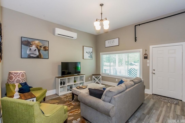 living area with a wall unit AC, wood finished floors, and a chandelier