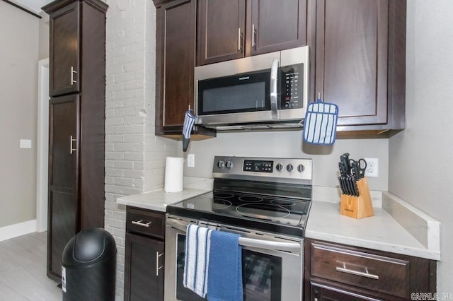kitchen with appliances with stainless steel finishes, dark brown cabinets, and light countertops