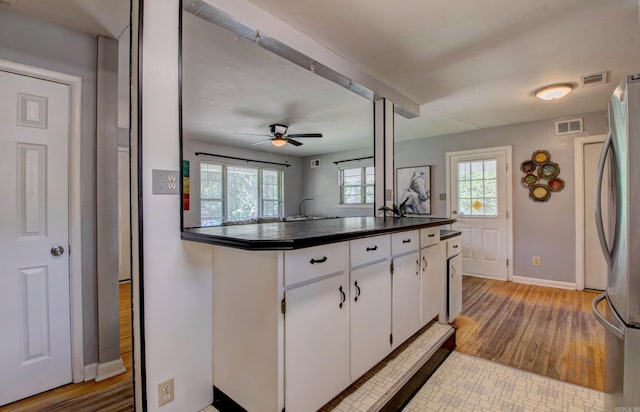 111 Greenland Cv, Little Rock, AR 72204 - kitchen with dark countertops, a ceiling fan, wood finished floors, white cabinets, and freestanding refrigerator
