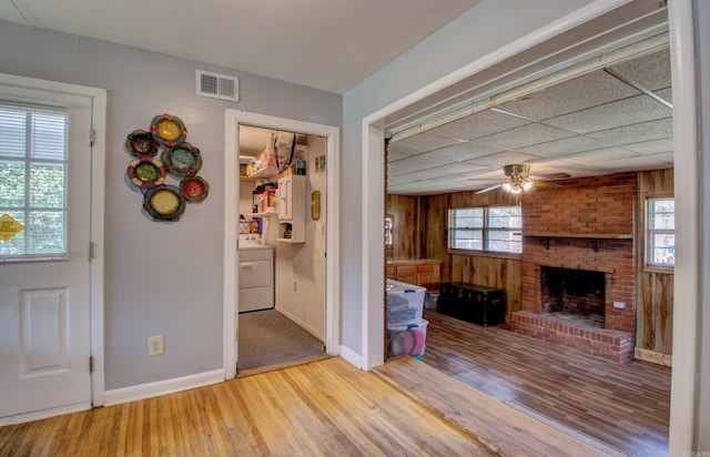 111 Greenland Cv, Little Rock, AR 72204 - unfurnished living room with washer / dryer, a ceiling fan, wood finished floors, a fireplace, and wood walls