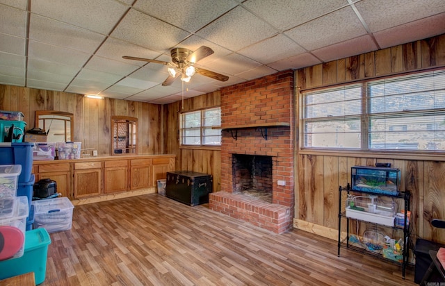 111 Greenland Cv, Little Rock, AR 72204 - kitchen featuring ceiling fan, wooden walls, light wood-style floors, a brick fireplace, and a paneled ceiling